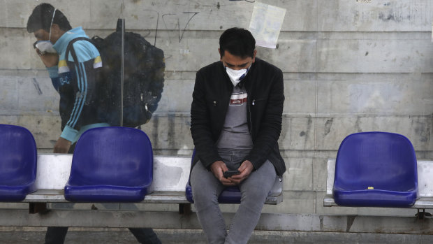 A man waits at a bus stop in Niavaran, northern Tehran, where officials have begun easing the lockdown.