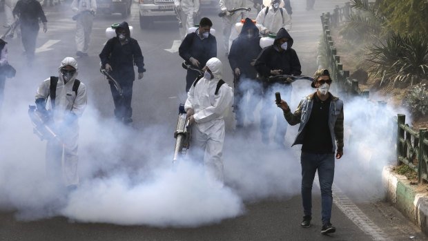 Firefighters disinfect a square against the new coronavirus in western Tehran, Iran.