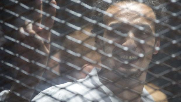 Mahmoud Abu Zaid, a photojournalist known as Shawkan smiles inside a cage in an Egyptian Court in Cairo, Egypt, on Saturday.