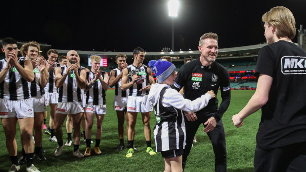 Magpies head coach Nathan Buckley celebrates victory with sons Ayce Buckley (L) and Jett Buckley (R) after coaching his final game.