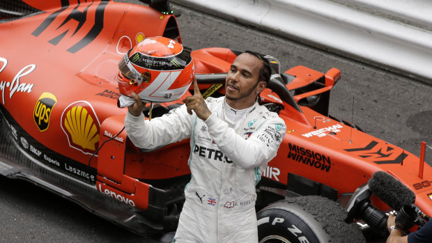 Mercedes driver Lewis Hamilton holds his red helmet to tribute Niki Lauda after he won the Monaco Grand Prix.