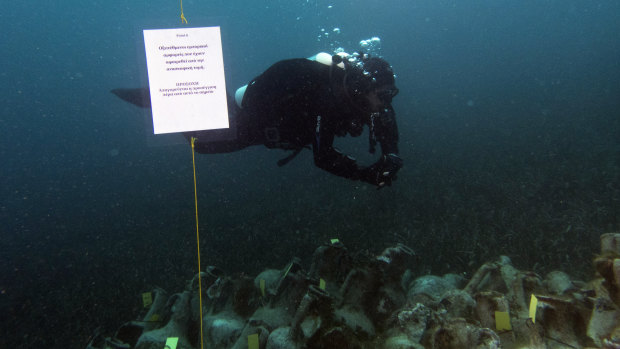 An archaeologists dives next ancient amphoras from a 5th century B.C. shipwreck, the first ancient shipwreck to be opened to the public in Greece.