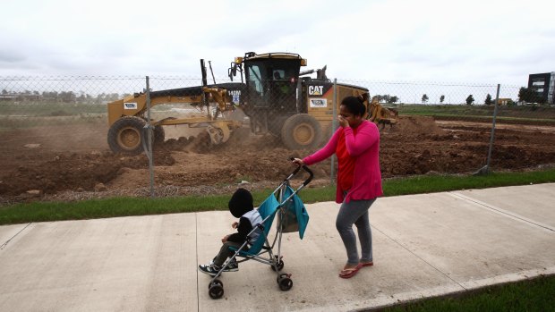 A woman pushes her child past  construction near the town centre.
