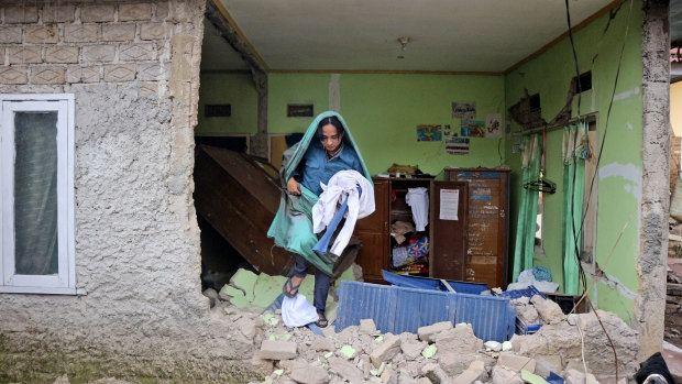 A resident collects clothing from a damaged house in Cianjur.