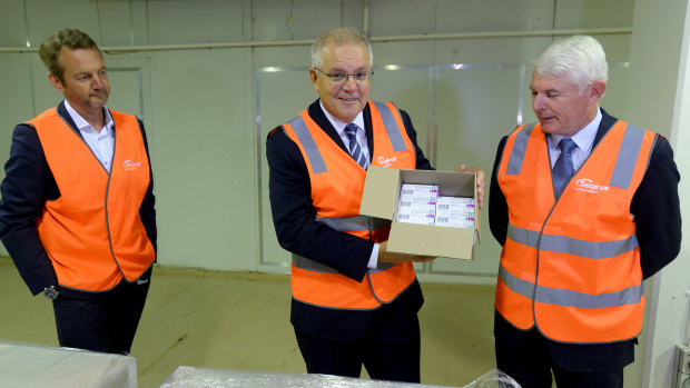 Prime Minister Scott Morrison, with Simon Buensch, executive director of manufacturing at CSL, and Dr Brian McNamee, chairman of CSL board, holds a box of AstraZeneca vaccines at the CSL factory in Melbourne last month.