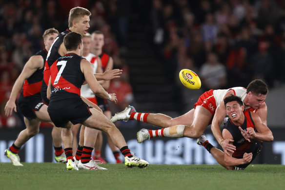 Essendon’s Jye Caldwell gets a handball away under a crunching tackle.