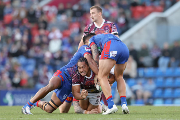 Manly’s Martin Taupau is wrapped up by the Knights defence.