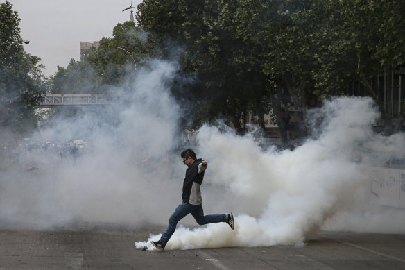 A protester kicks a tear gas canister launched by police during a protest in Santiago, Chile, on Saturday.