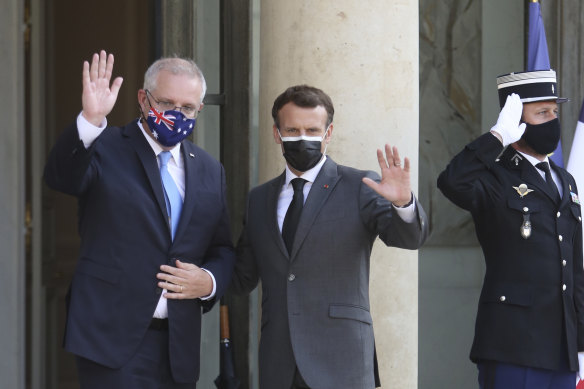 French President Emmanuel Macron, center, and Australia’s Prime Minister Scott Morrison wave to reporters before a working dinner at the Elysee Palace in Paris, Tuesday, June 15, 2021.