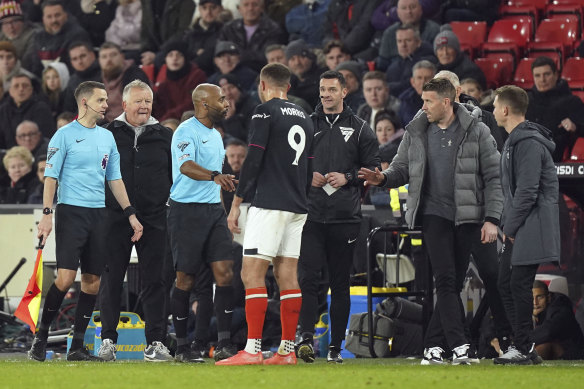 Luton’s Carlton Morris, centre, speaks with referee Sam Allison as both managers look on.