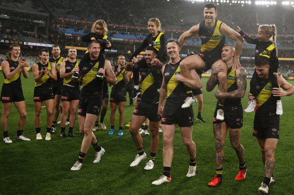 Trent Cotchin is carried off by Dustin Martin and Jack Riewoldt.