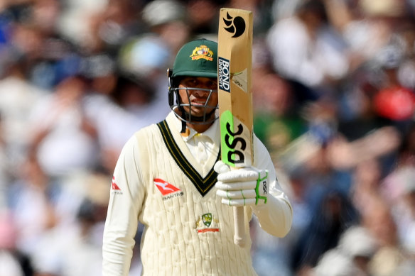Usman Khawaja of Australia raises his bat after reaching a half-century on day five of the first Test.