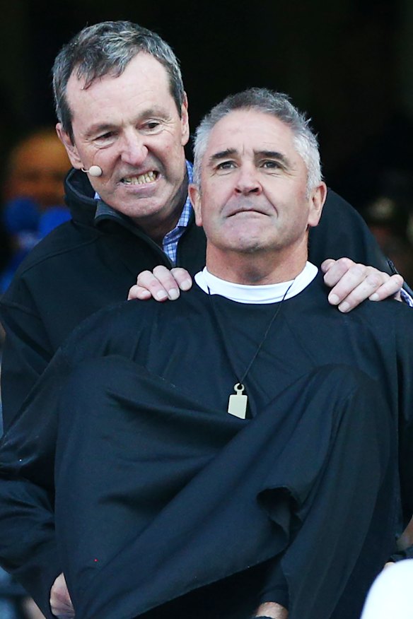 Neale Daniher pushes Chris Fagan down the slide.