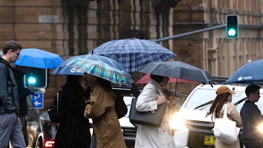 People crossing a Sydney CBD street in the rain on Thursday.