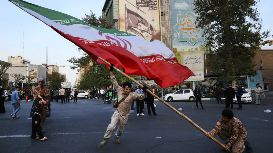 Demonstrators wave a huge Iranian flag backdropped by a building emblazoned with anti-Israeli messages, in Tehran, Iran, on Monday.