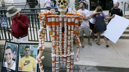 A skeleton made of pill bottles stands with protesters outside a courthouse in Boston, where a judge was hearing arguments against opioid maker Purdue Pharma.
