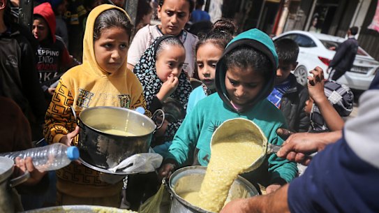 Displaced Palestinians receive cooked food rations in Deir-al-Balah in the central Gaza strip.
