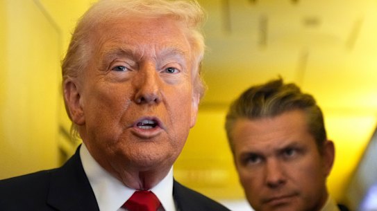 President Donald Trump speaks to reporters as War Secretary Pete Hegseth listens while travelling aboard Air Force One to Miami on the weekend.