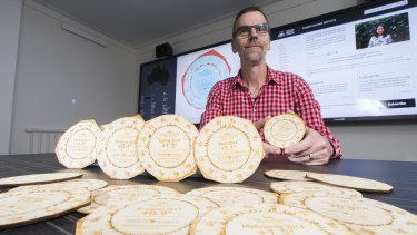 Dr Geoff Hinchcliffe from the ANU School of Art and Design with coasters made from laser cut wood showing the climate shift for an Australian city.