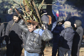 A migrant carries firewood as other migrants from the Middle East and elsewhere gather at the Belarus-Poland border near Grodno, Belarus.