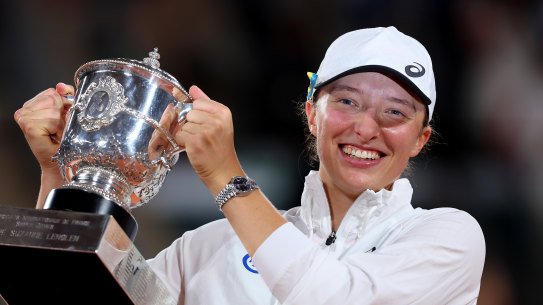 Iga Swiatek of Poland celebrates with the trophy after beating Coco Gauff.