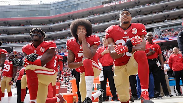 Colin Kaepernick (centre) kneeling in protest. 