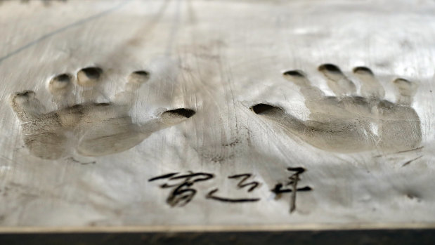 Xi Jinping's handprints are imprinted on a wet clay slab during the BRICS Summit in Johannesburg.