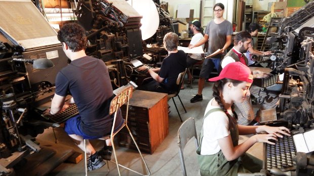 The museum's 'newspaper composing room' with people posing as Linotype as operators and (standing) a copy boy, handing out the  text the typesetters will compose. 