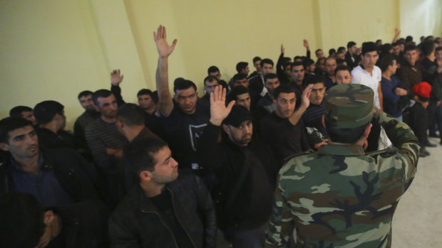Azerbaijani men gather in a military commissariat to join the army in Tartar region, Azerbaijan.