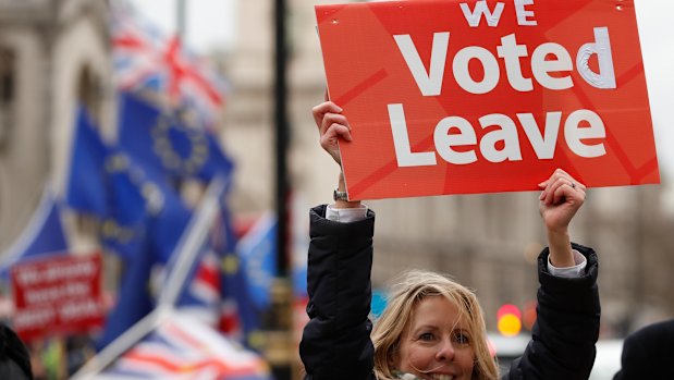 A pro-Brexit demonstrator waves a placard with others outside the Houses of Parliament in London.