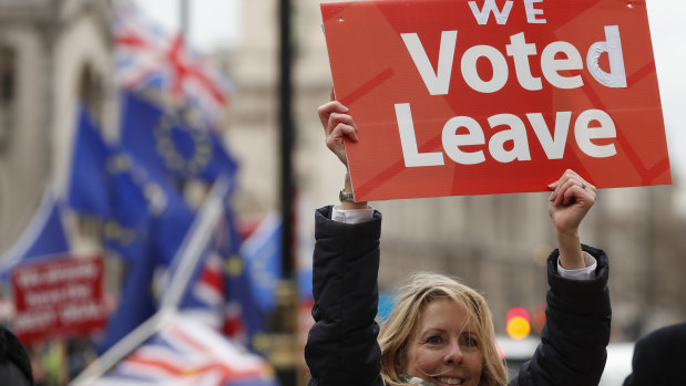 A pro-Brexit demonstrator waves a placard with others outside the Houses of Parliament in London.