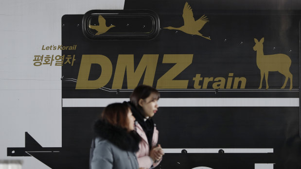 Visitors walk past a train carrying letters "Peace train" and "DMZ train" at Imjingang Station in Paju.
