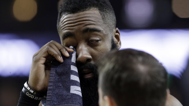James Harden wipes his injured eye with a towel.