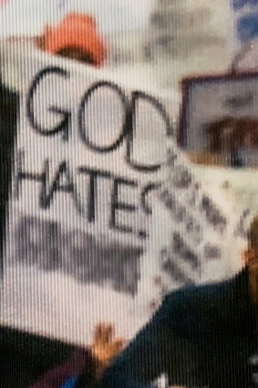 This is a close-up of an altered sign in a photograph from the Women's March in 2017 that is on display at the National Archives in Washington, DC. The original image is populated with a variety of signs. At least four of the signs are altered.
