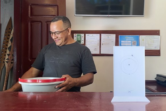 Hotel owner Rubeney de Castro Alves stands near a Starlink router installed at his front desk in Atalaia do Norte, in Brazil’s Amazon. The fast internet connection has improved his business.