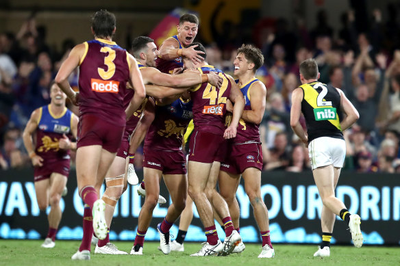Brisbane players crowd around James Madden after his goal.