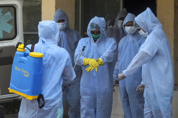 Municipal workers in protective suits sanitise themselves after cremating a COVID-19 victim in Mumbai on Thursday.