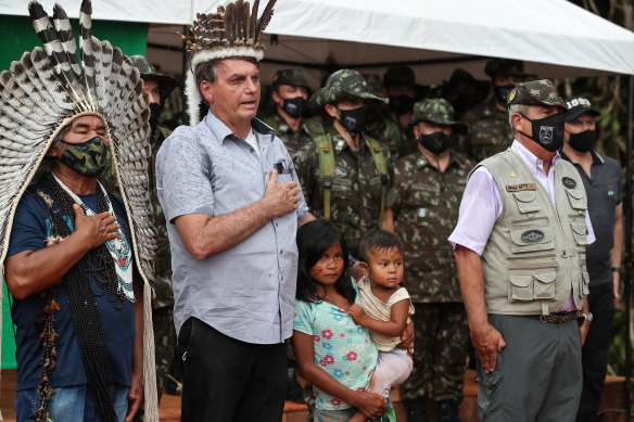 Brazilian President Jair Bolsonaro, second from left, sings the national anthem at a ceremony to open the new bridge leading to an area where major reserves of niobium have been found. 