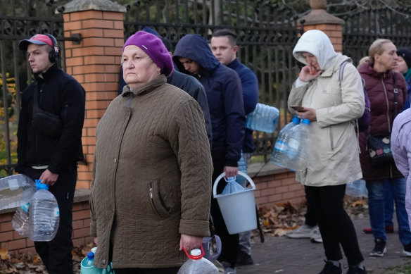 A woman waits to fill containers with water from public pumps in Kyiv.