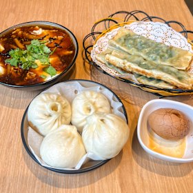 No sentido horário, a partir do canto superior esquerdo: pudim de tofu Douhua, bolinhos de cebolinha, ovo de chá e pães cozidos no vapor com carne de porco e cebolinha.