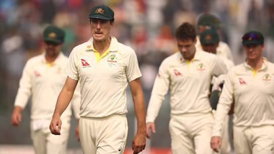 Pat Cummins leads the dejected Australians from the field in Delhi.