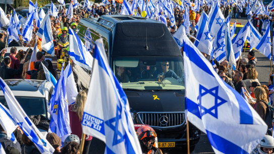 Thousands of people line the entrance to the Ayalon highway to watch and pay their respects as the funeral procession carrying the caskets of Shiri, Kfir and Ariel pass by with the family in minibuses behind them.