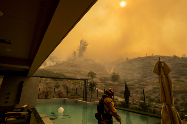 In California, an Orange County firefighter prepares to defend a home as the Silverado fire approaches a neighborhood in October 2020.