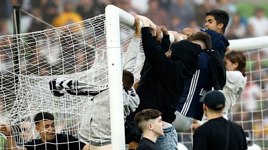 Fans swing on the goal after storming the pitch at AAMI Park on Saturday night.