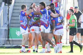 Newcastle players celebrate Edrick Lee’s try against the Warriors.
