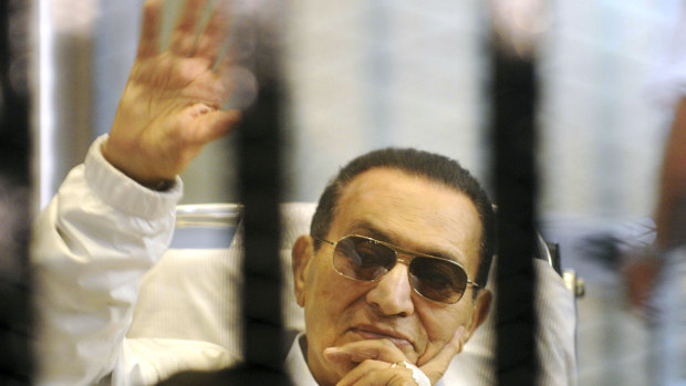 Hosni Mubarak waves to his supporters from behind bars as he attends a hearing in his retrial on appeal in Cairo on April 13, 2013.