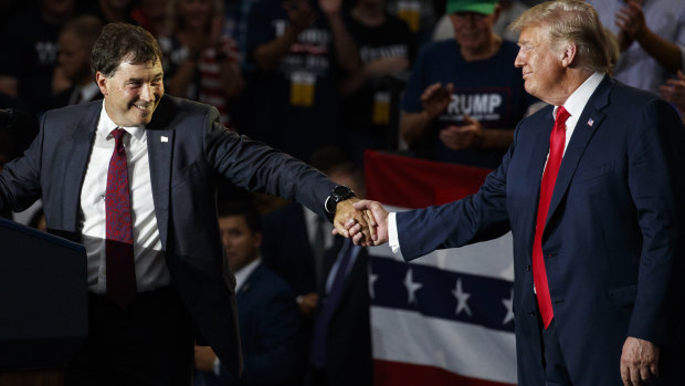 Troy Balderson, left, reaches for Donald Trump's hand as he speaks at a rally at Olentangy Orange High School in Lewis Center, Ohio, on Saturday.