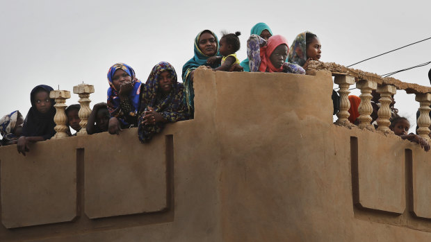 Sudanese stand on their roof top house, as they watch the arrival of General Abdel-Fattah Burhan, head of the military council, during a military-backed rally, in Omdurman district, west of Khartoum, Sudan on Saturday. 