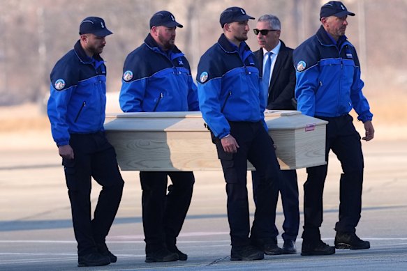 Police officers carry the coffin of an Italian teenager killed in the Swiss fire on to a plane at Sion airport.