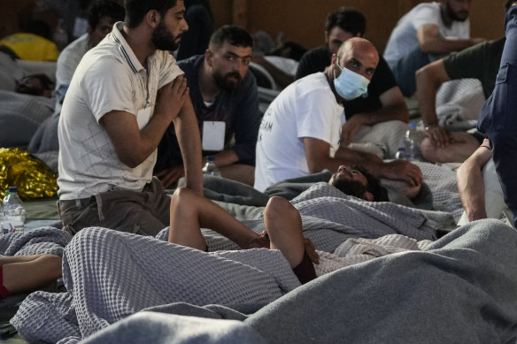 Survivors of a shipwreck rest in a warehouse at the port in Kalamata.